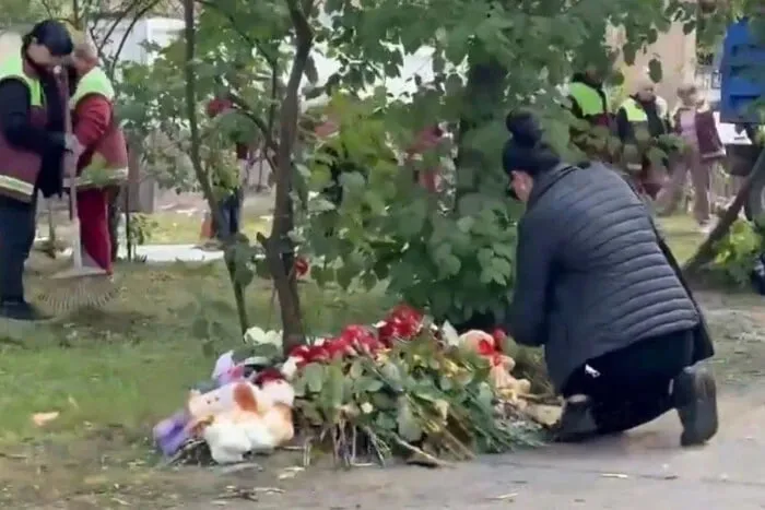 В Киеве в День траура люди приносят цветы к разрушенному дому после атаки РФ